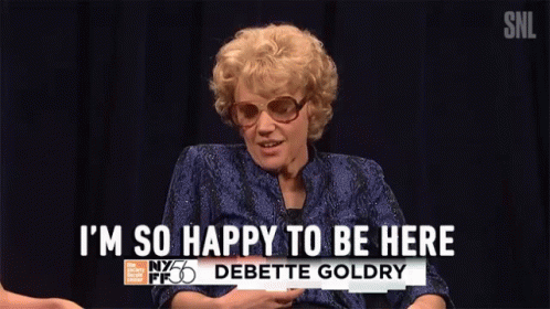 a woman in a blue shirt and sunglasses is saying i 'm so happy to be here