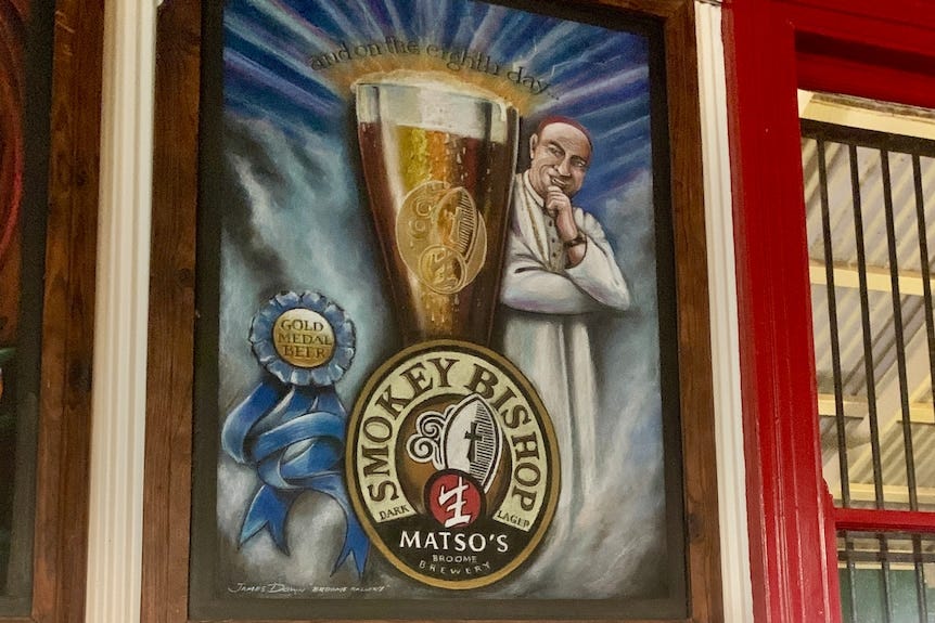 A large advertising image of a Catholic cleric smiling next to a large glass of beer, hanging on a wall