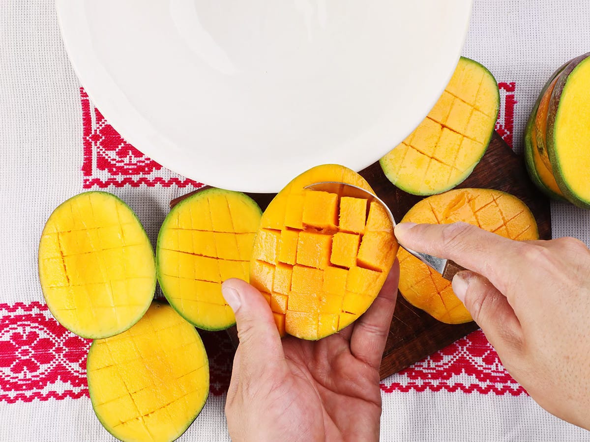 scooping mangos with a spoon