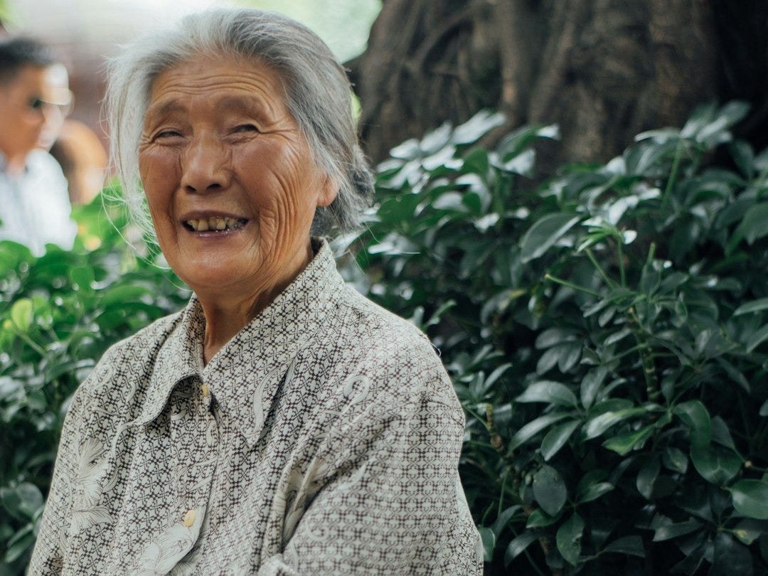 smiling woman sitting on bench under the tree smiling woman sitting on bench under the tree