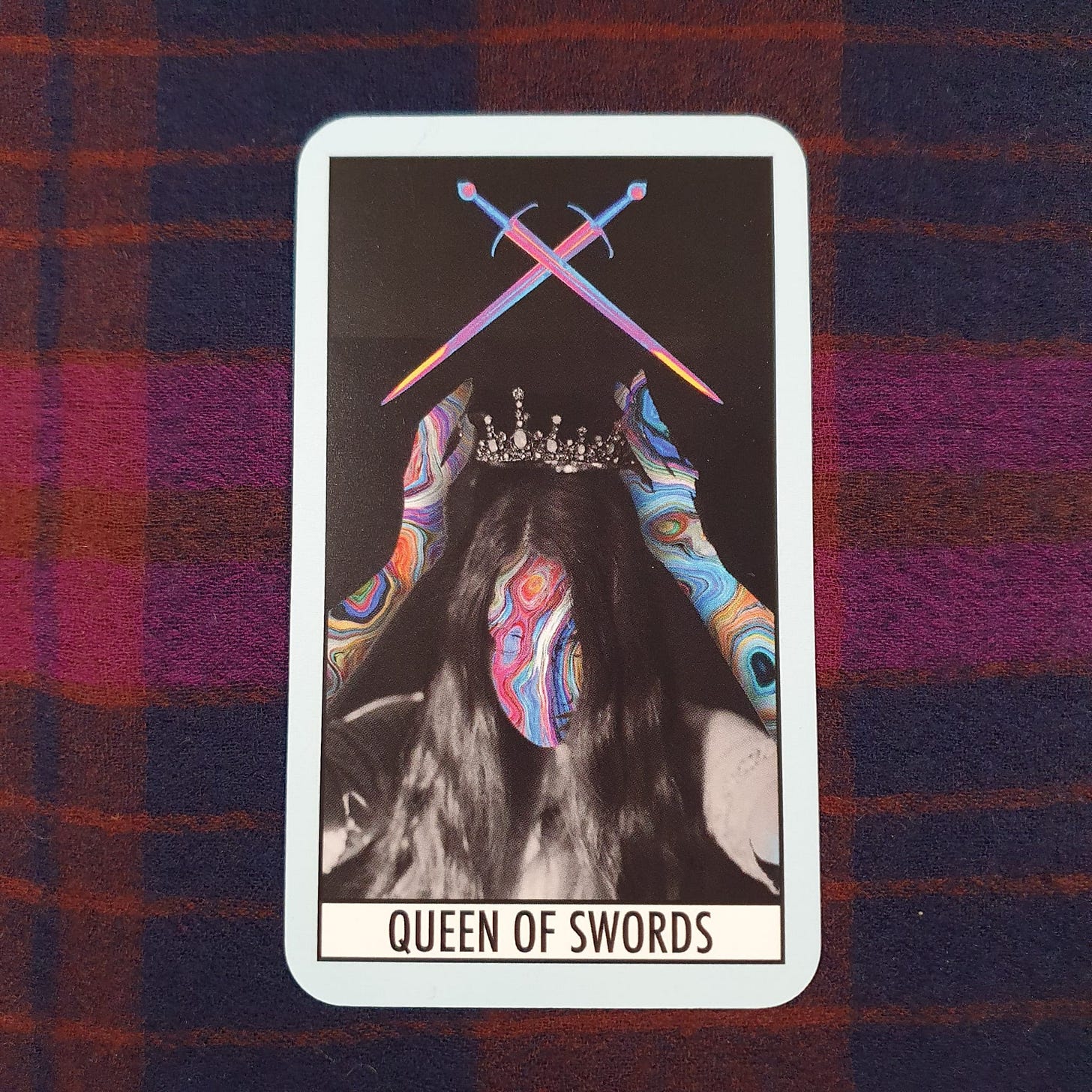 Queen of Swords card from The Theatre Deli Tarot, featuring a crowned figure with a vivid psychedelic face and crossed swords above her head on a black background. Gift card in Amy Twigg’s Tarot DMs interview, used to discuss precision, boundaries, editing and fierce feminine intelligence. Queen of Swords card from The Theatre Deli Tarot, featuring a crowned figure with a vivid psychedelic face and crossed swords above her head on a black background. Gift card in Amy Twigg’s Tarot DMs interview, used to discuss precision, boundaries, editing and fierce feminine intelligence.