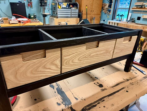Three views of a wooden bench with drawers. Left: natural wood drawer fronts fitted into the frame. Center: drawers painted dark with visible wood grain. Right: completed bench with smooth black finish across all drawers.