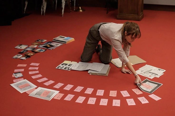 This may contain: a woman kneeling down on the floor with papers and pictures laid out in front of her