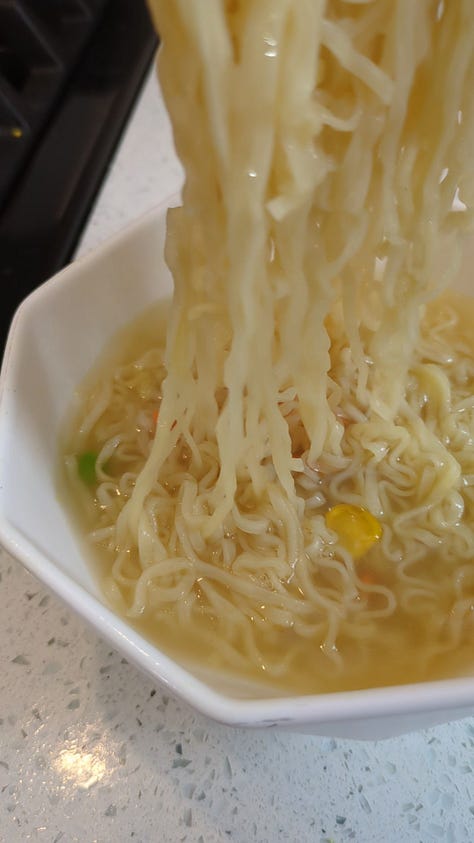 Classic chicken instant ramen cup being opened, cooked, and held up by chopsticks.