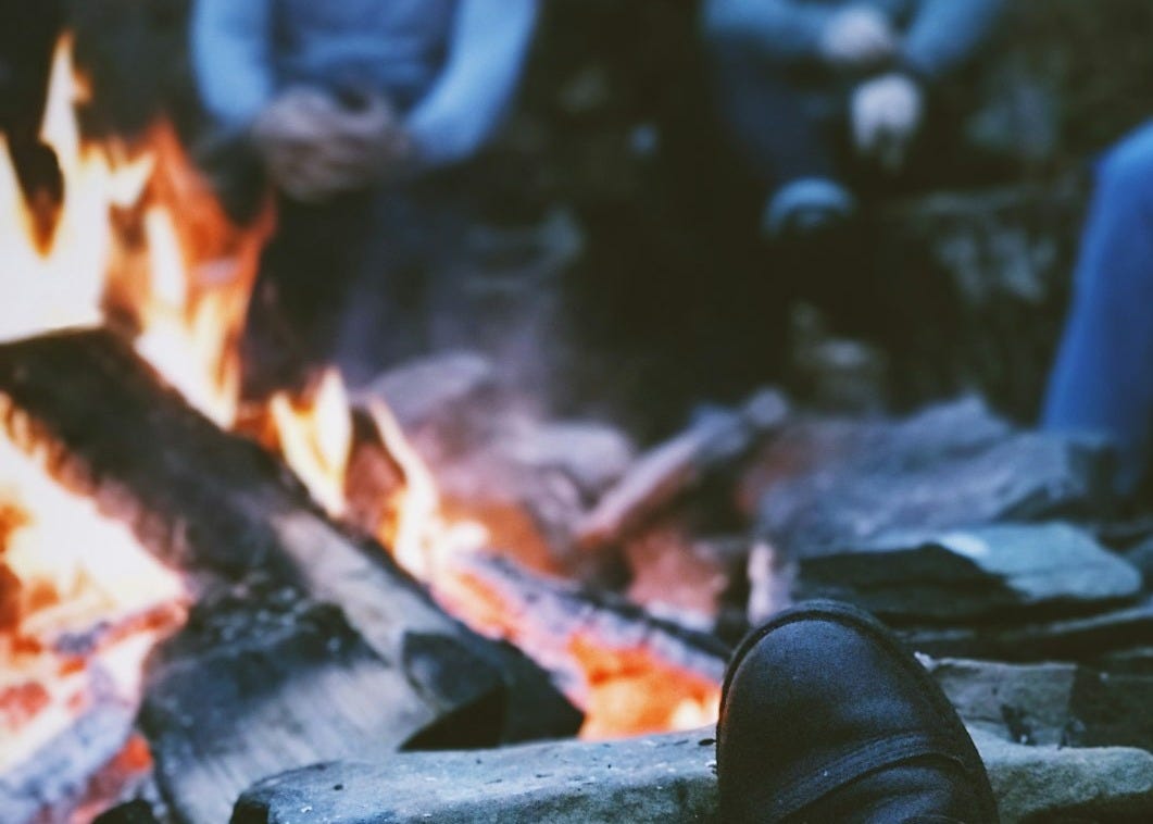 a person's feet sitting in front of a fire a person's feet sitting in front of a fire