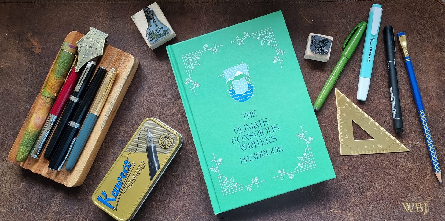 photograph of the front cover of The Climate-Conscious Writers Handbook, alongside pens and pencils