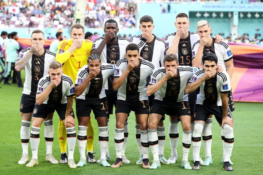 Germany players pose with their hands covering their mouths as they line up for the team's photo prior to the World Cup game against Japan.