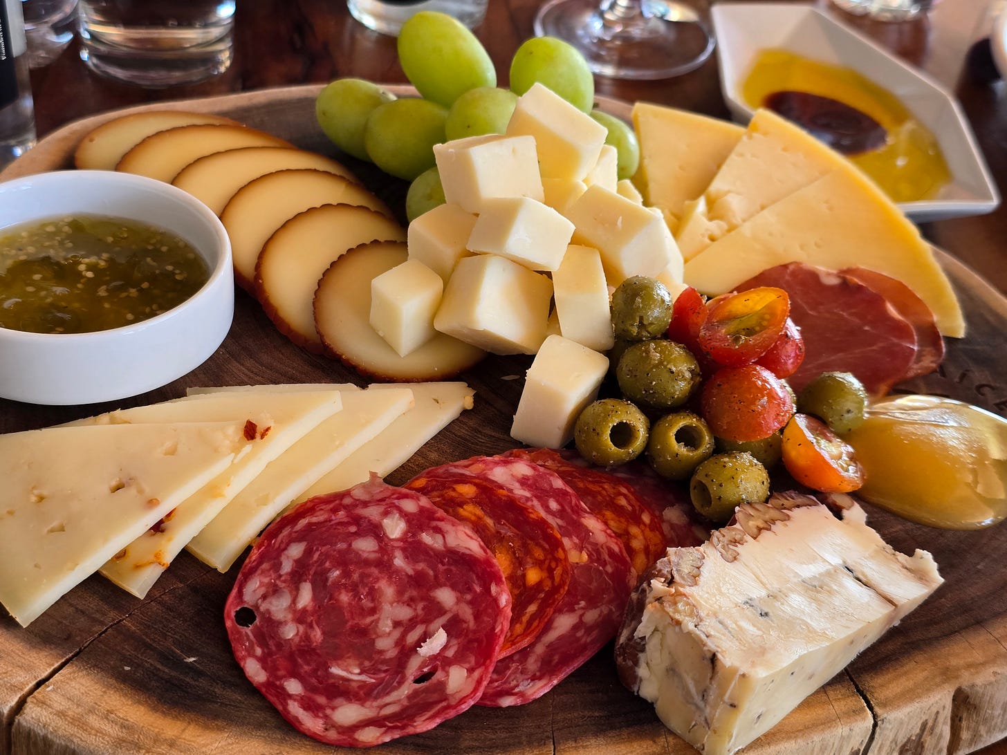 A plate with cheese, meat, olives, and fruit