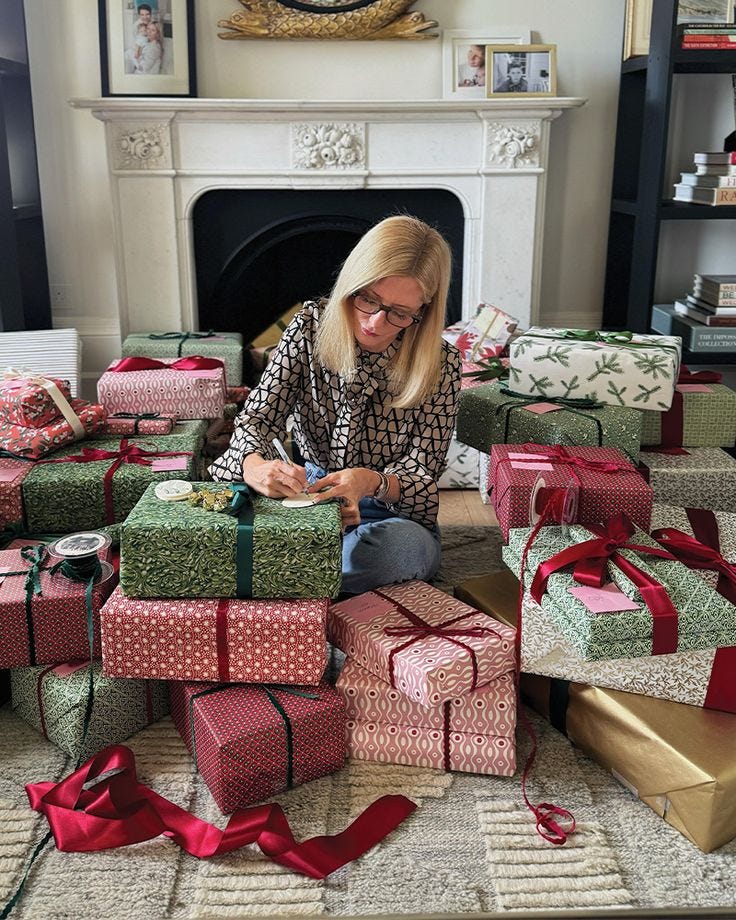 This may contain: a woman sitting on the floor surrounded by presents This may contain: a woman sitting on the floor surrounded by presents