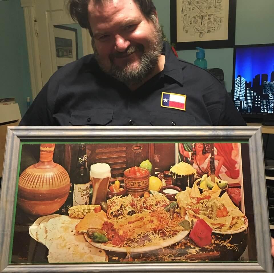 Pictured is a man in a navy blue shirt with the flag of Texas on it holding a framed copy of the art from the first picture. The elaborate Tex-Mex feast in all its glory. Pictured is a man in a navy blue shirt with the flag of Texas on it holding a framed copy of the art from the first picture. The elaborate Tex-Mex feast in all its glory.