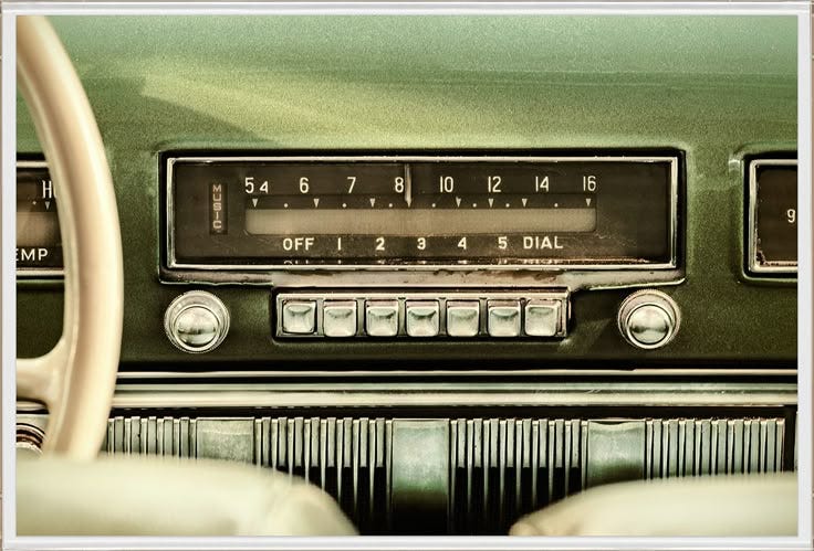 This may contain: an old radio sitting on top of a green car's dash board and steering wheel