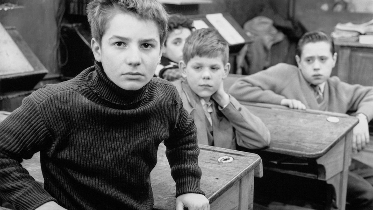 Still from The 400 Blows (1959): Antoine Doinel sits defiant at his school desk, surrounded by classmates. His expression captures the quiet fury and alienation that launched a cinematic revolution. Still from The 400 Blows (1959): Antoine Doinel sits defiant at his school desk, surrounded by classmates. His expression captures the quiet fury and alienation that launched a cinematic revolution.