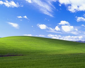 Rolling green hills under blue sky with white clouds.