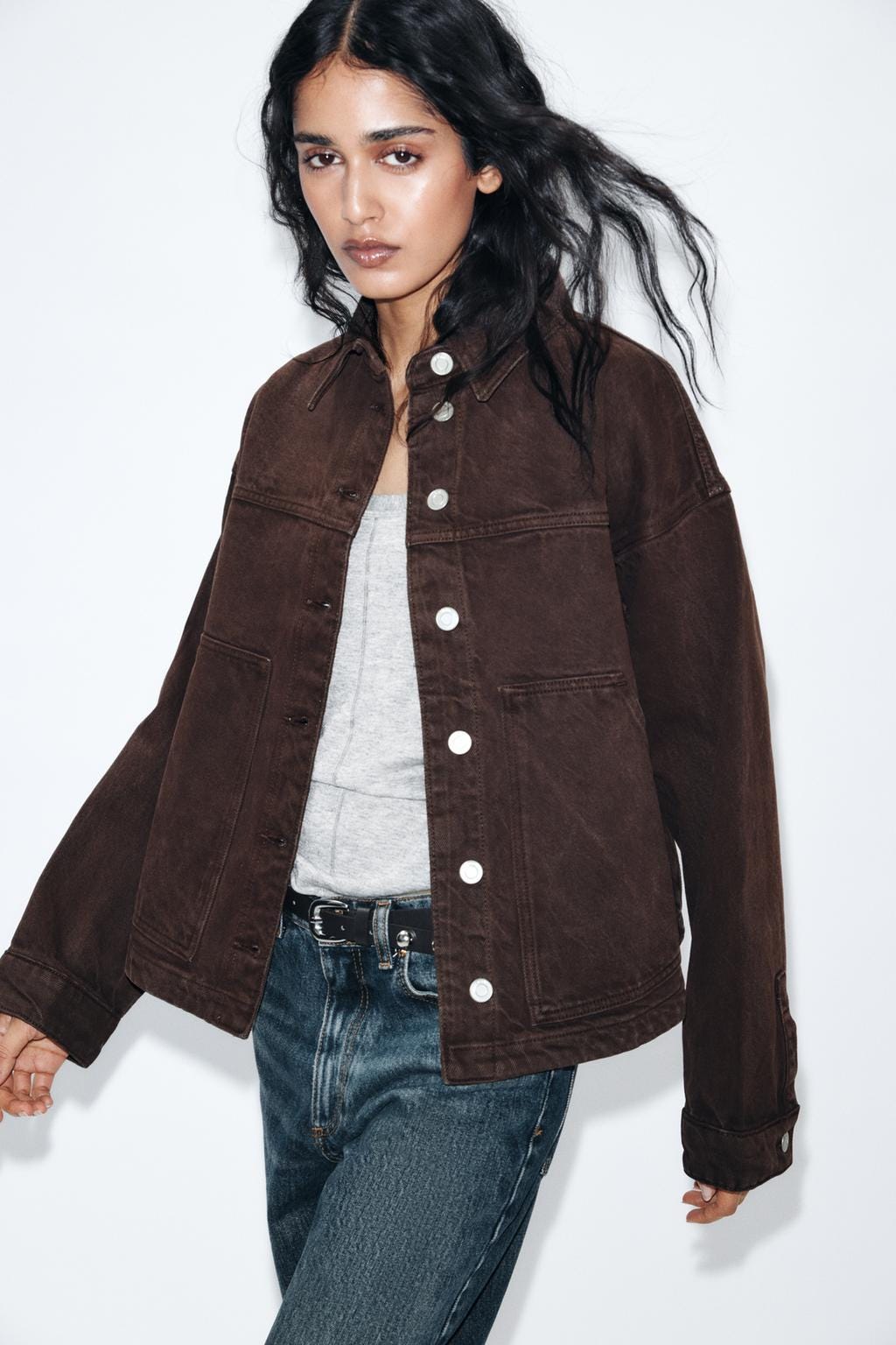 Brown jacket set with white buttons, grey t-shirt, and dark blue jeans. Visible front pockets.