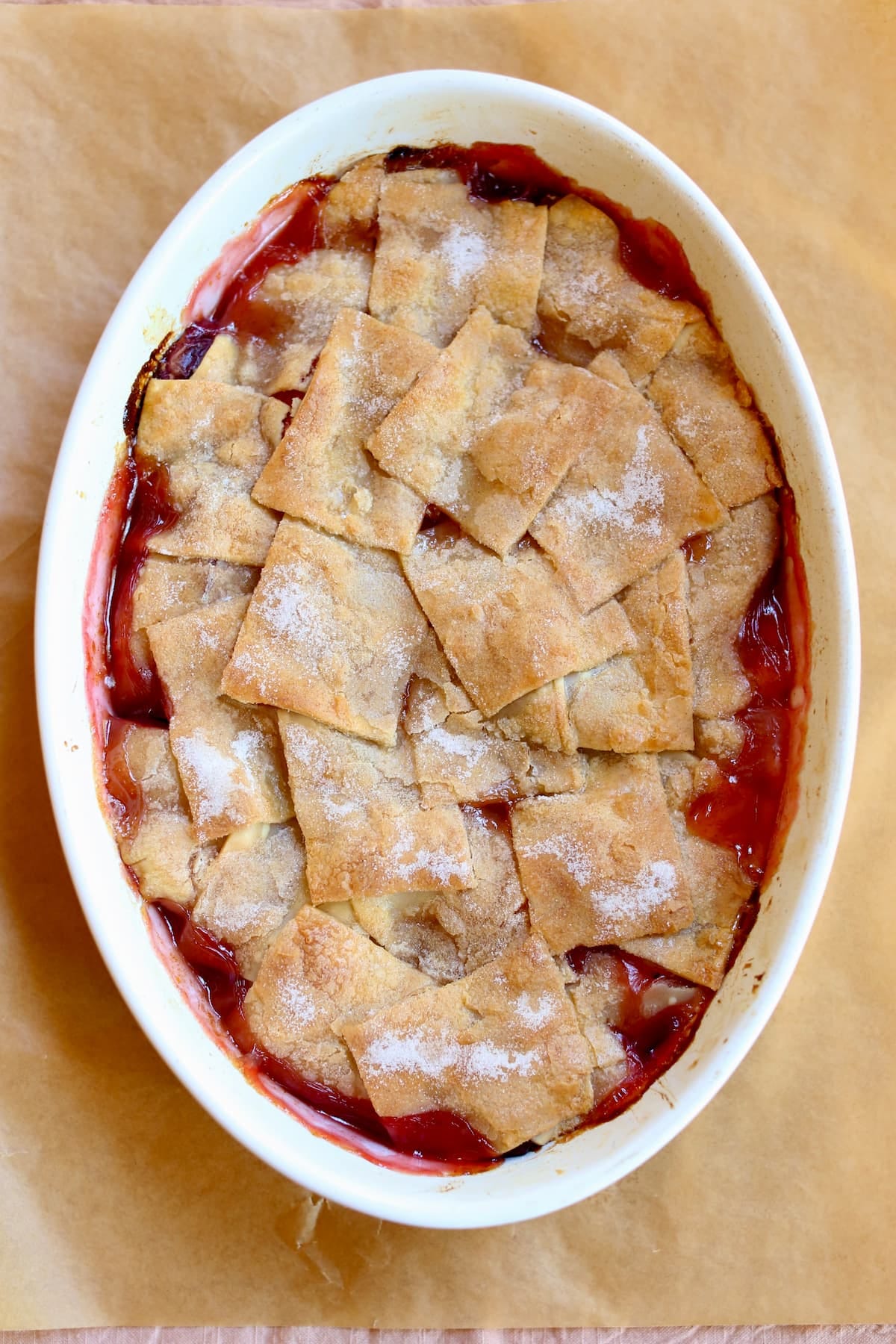 a peach cobbler in a white baking dish.