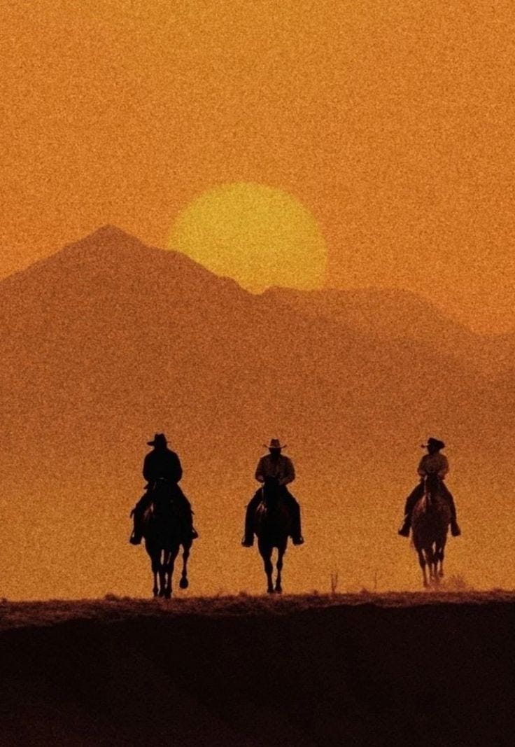 This may contain: three people riding horses in the desert at sunset This may contain: three people riding horses in the desert at sunset