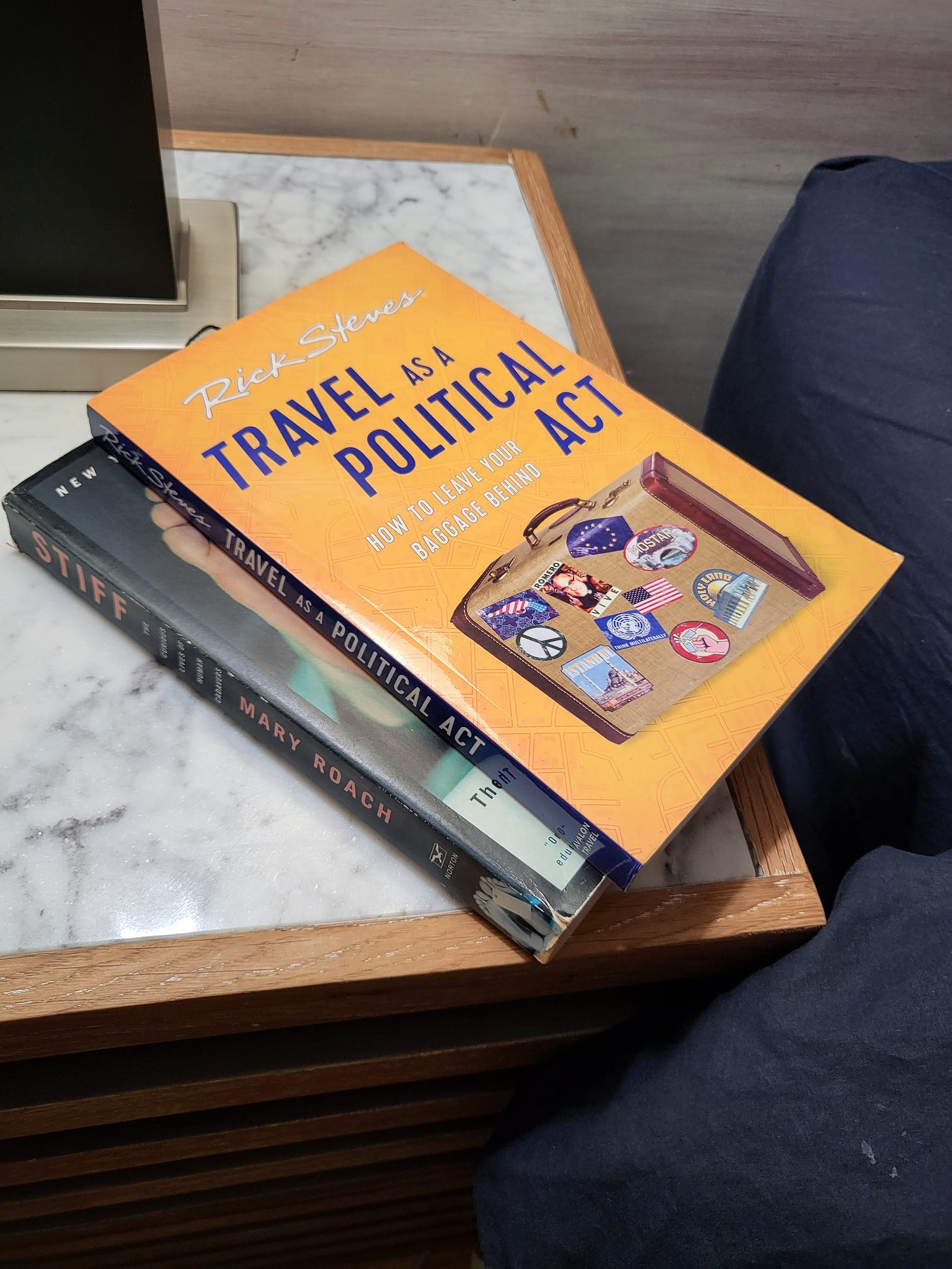 Photo taken by Melanie of her nightstand, with Rick Steves' Travel as a Political Act sitting atop another book on the white and grey table top
