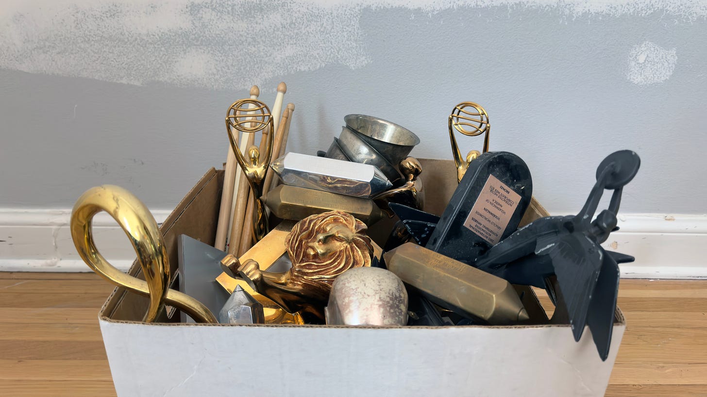 Box of advertising award trophies won by Tim Brunelle, in front of a wall that clearly needs painting