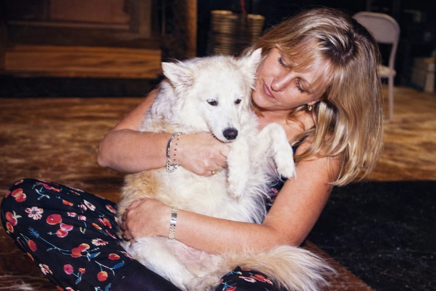 A pretty woman holding a white fluffy dog in her lap.