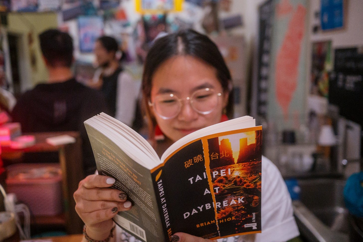 Photo of a close-up shot of a reader flipping through Brian Hioe's novel Taipei at Daybreak.