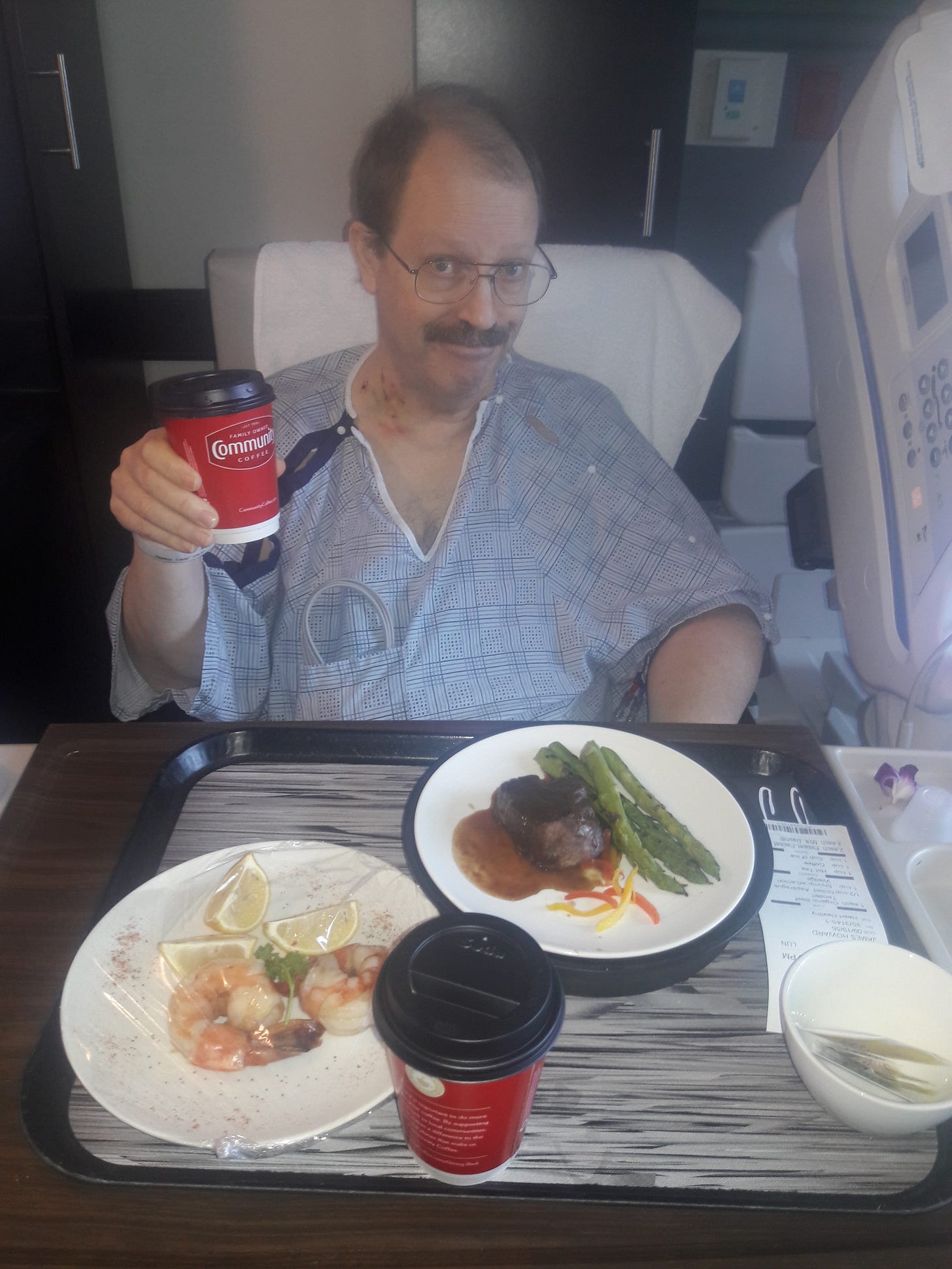 Man in hospital bed holding a cup of coffee