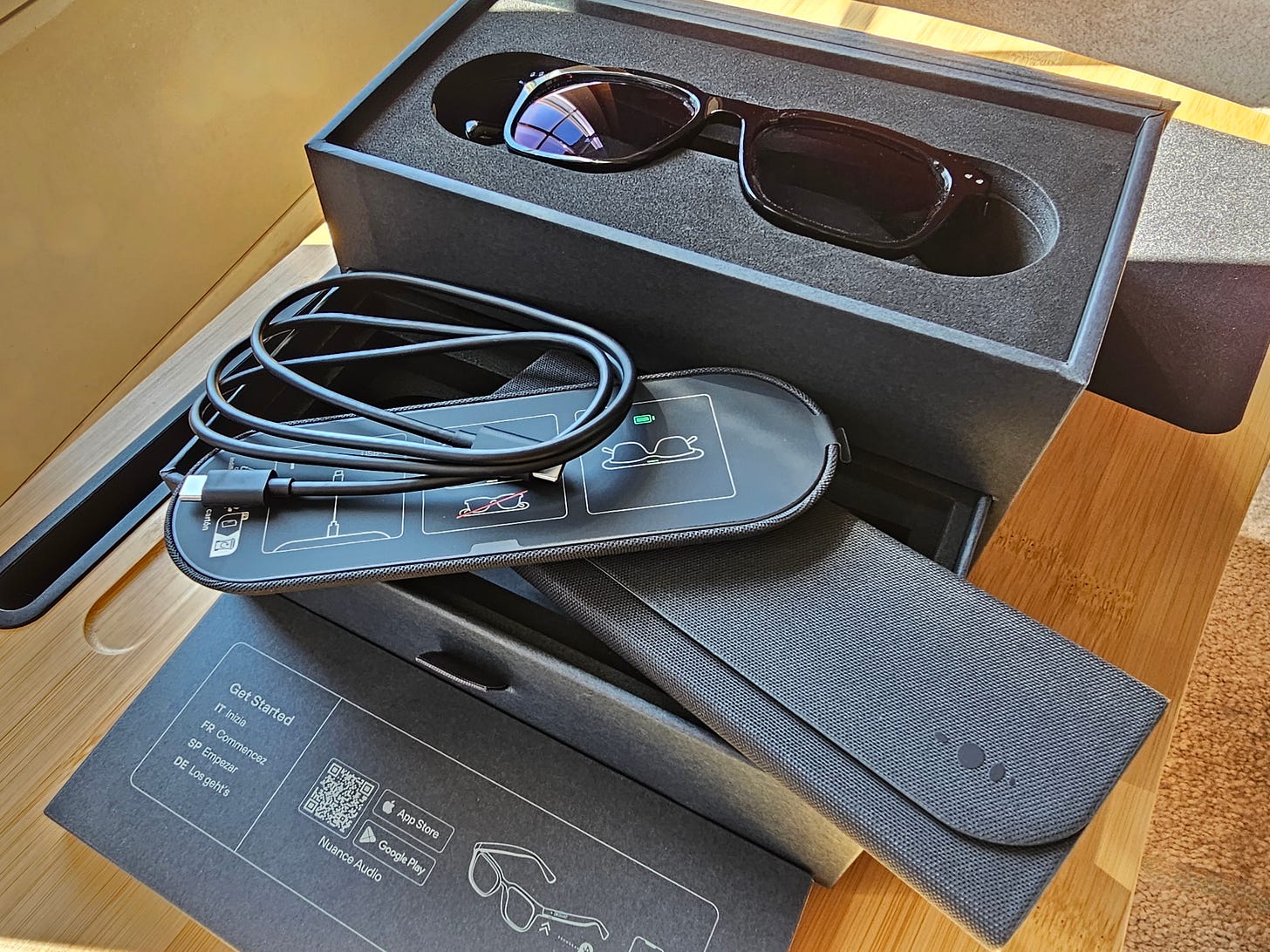 Open box: Nuance Audio Hearing Glasses, a USB charging cord, charging dock, and travel case.