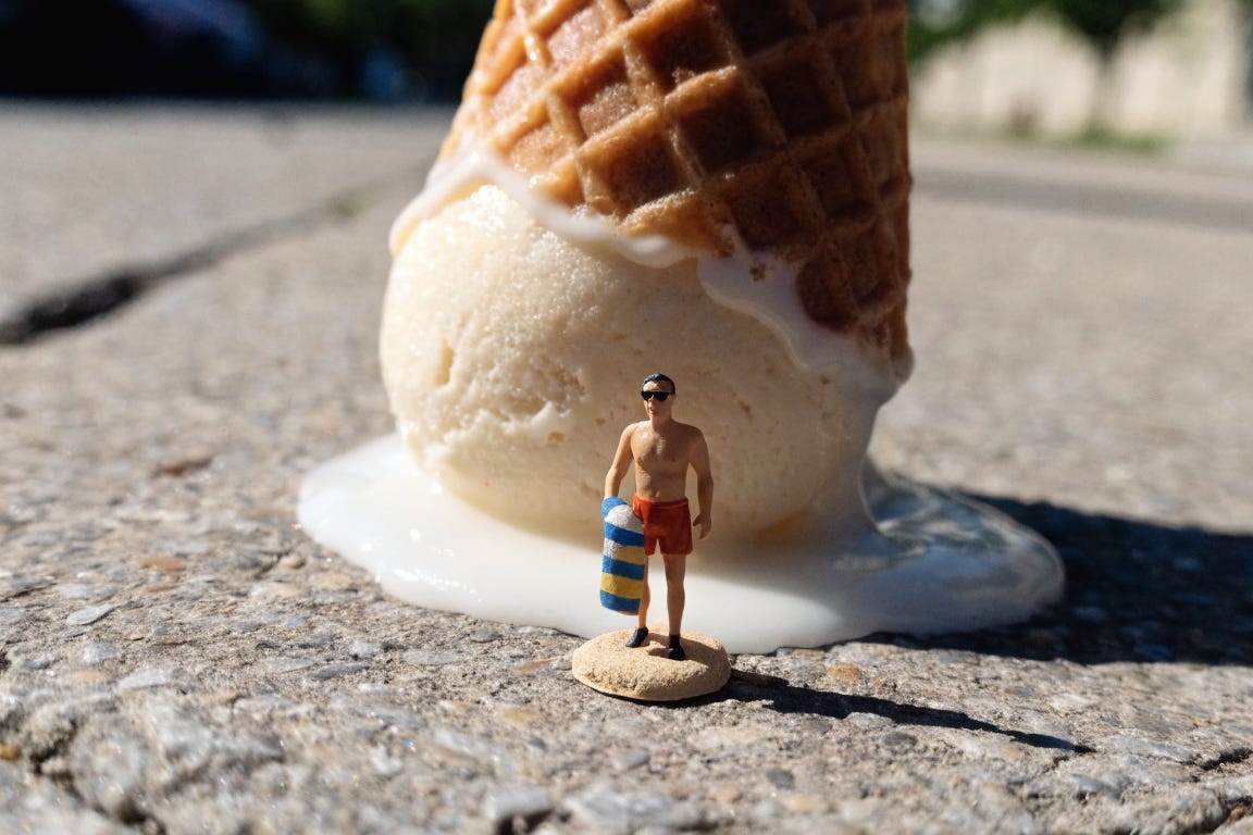 A tiny plastic figurine of a man wearing swimming trunks and dark glasses holding a beach towel, on a plastic base painted to look like sand. Behind him is an ice-cream cone with a scoop of melting vanilla ice-cream leaving a white puddle. A tiny plastic figurine of a man wearing swimming trunks and dark glasses holding a beach towel, on a plastic base painted to look like sand. Behind him is an ice-cream cone with a scoop of melting vanilla ice-cream leaving a white puddle.
