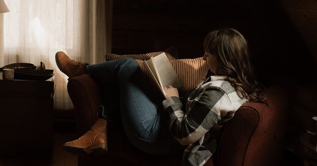 Sarah K of Make For Good reading a book in a cozy chair by a window, soft natural light in a quiet, cabin-like room evoking rest and slow living Sarah K of Make For Good reading a book in a cozy chair by a window, soft natural light in a quiet, cabin-like room evoking rest and slow living