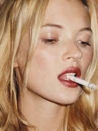 Kate Moss in the early 90s wearing a off-duty veil of lip colour while smoking a cigarette | The Beauty Ed®