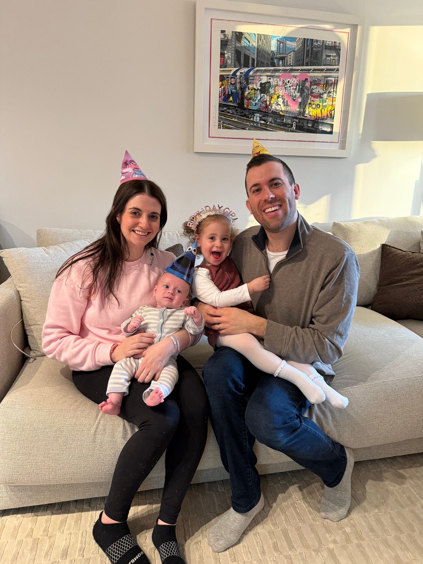 Ian Teckline with his wife and kids sitting on a couch wearing party hats