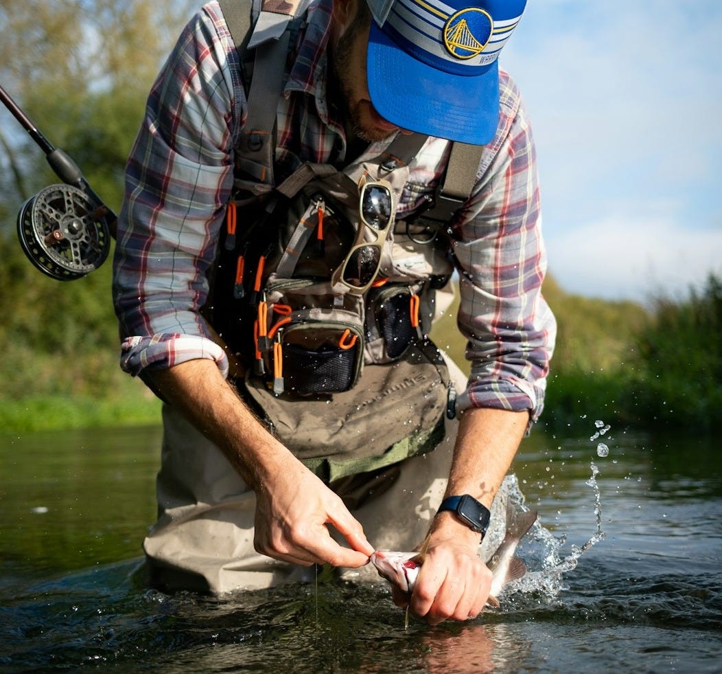 a man standing in a river holding a fish a man standing in a river holding a fish