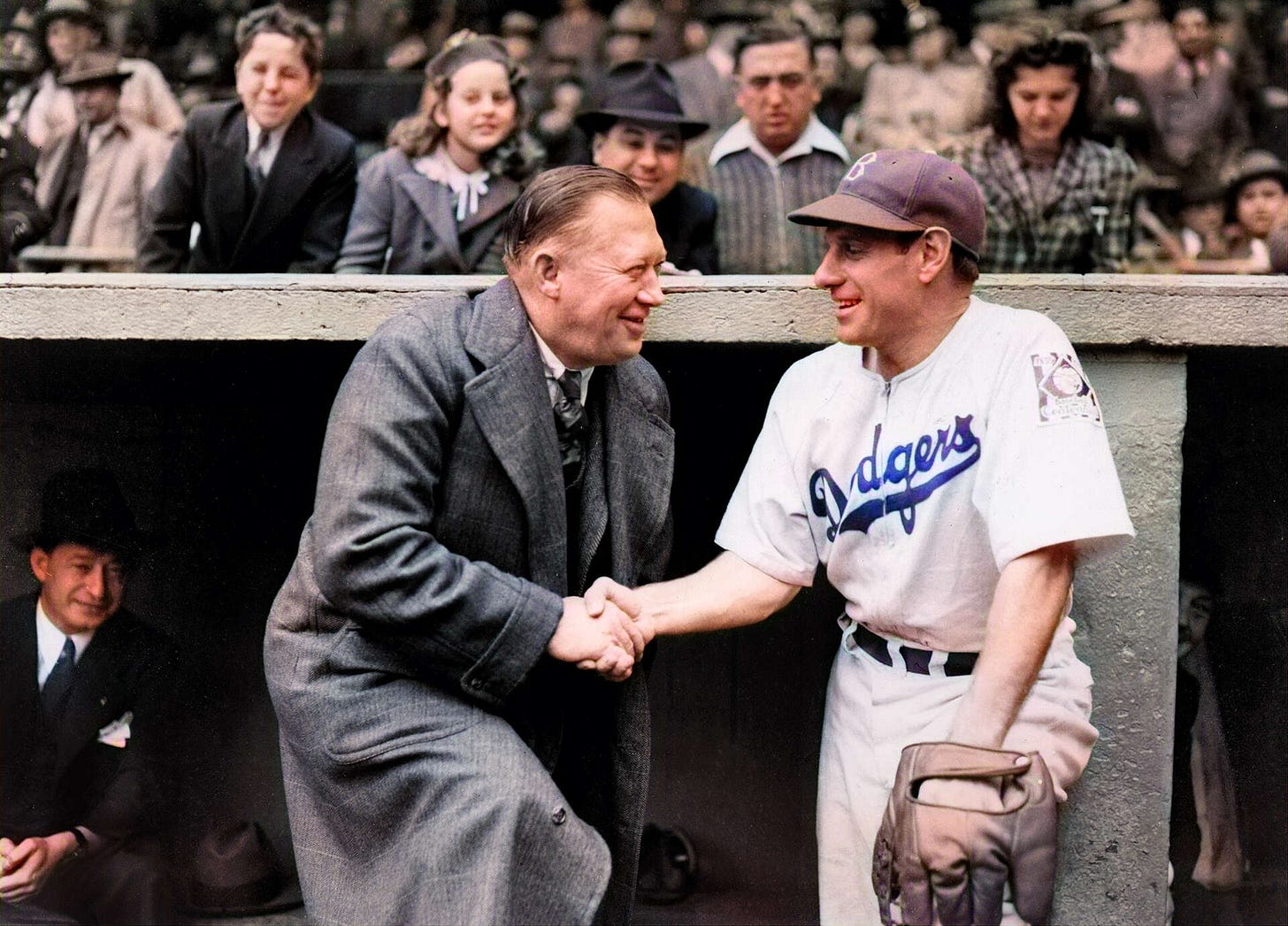 Larry MacPhail shakes Leo Durocher's hand in front of the dugout.