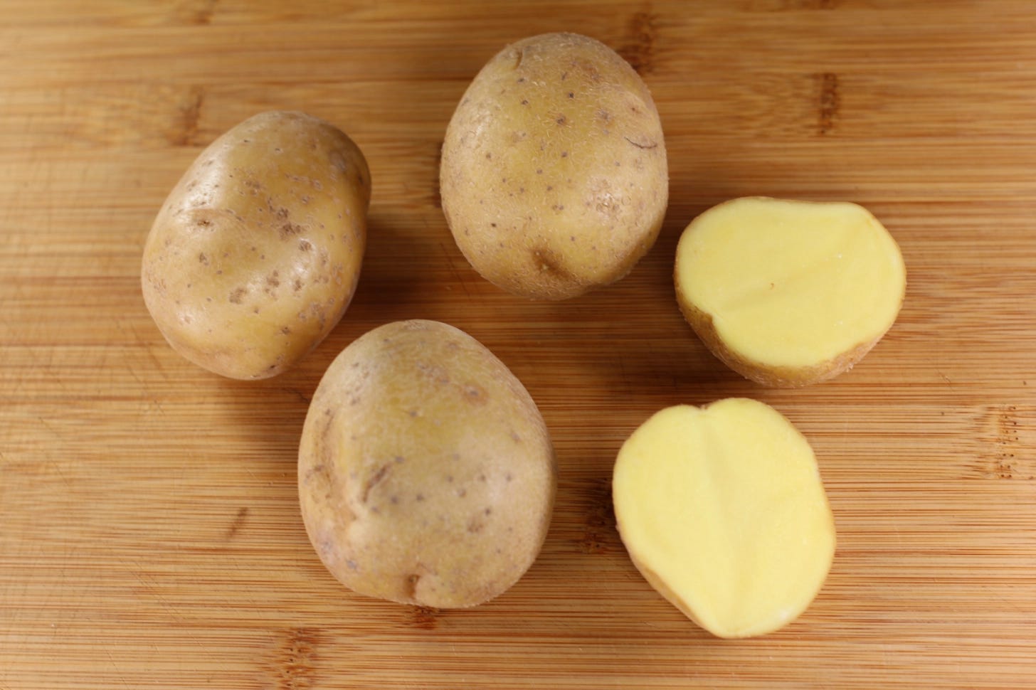 A styled photo of Yukon Gold Potatoes showing three whole and one cut.