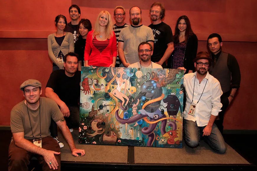 Group picture of the ten artists (in no particular order - Ana Bagayan, Glenn Barr, Dave Cooper, Bob Dob, Joe Ledbetter, Brandi Milne, Daniel Peacock, Shag, Amy Sol and Michael Whelan) posed with the collaborate “jam” piece they all worked on. Michael’s portion is ammonite fossils in the upper right. 