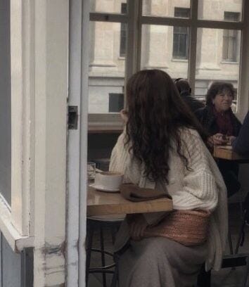 This may contain: two women sitting at a table in front of a window with their backs to the camera