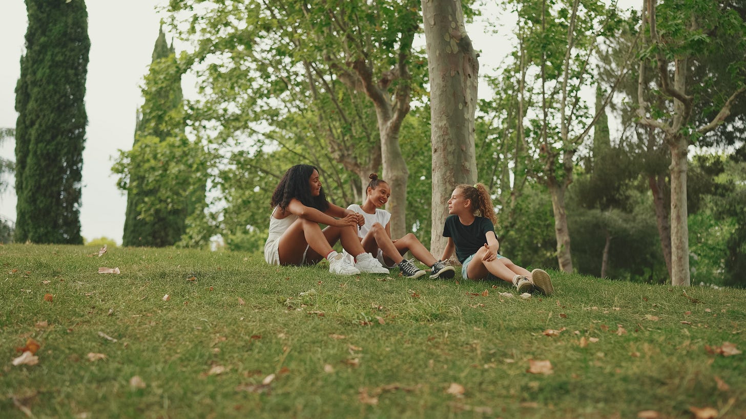 three teens sit outside on a hill three teens sit outside on a hill