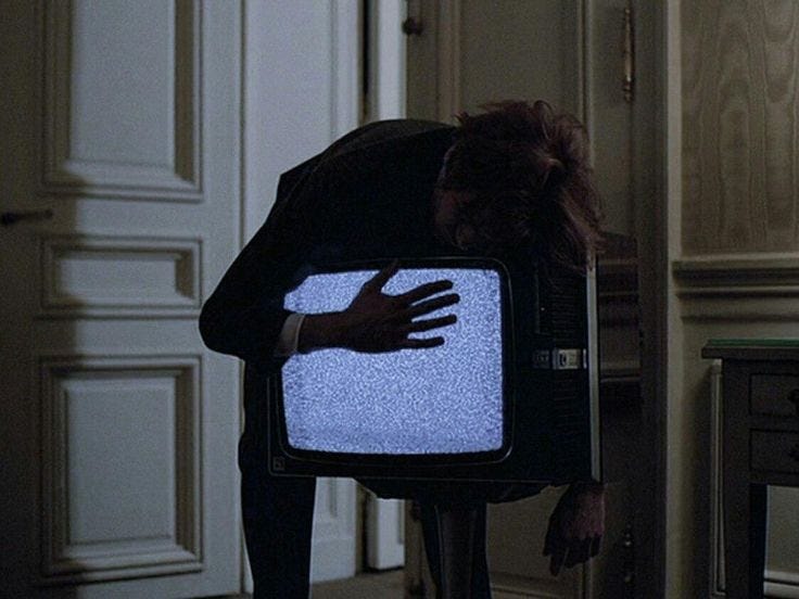 This may contain: a person bending over with their hand on a television set in the middle of a room