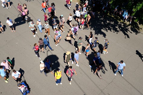 Overhead shot of attendees, friends in the gondola behind me on the Skyride, seed art wall at the Crop Art show, attendee looking over loaves of bread, amusement rides, golden hour behind the crowd, Sweet Martha's Cookies at night.