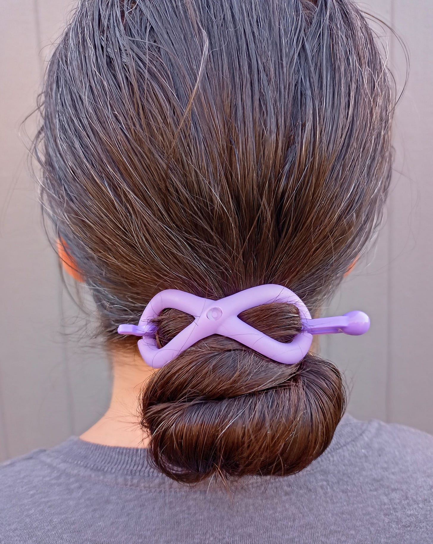 Woman with brown hair in a low bun with purple Flexi hair clip