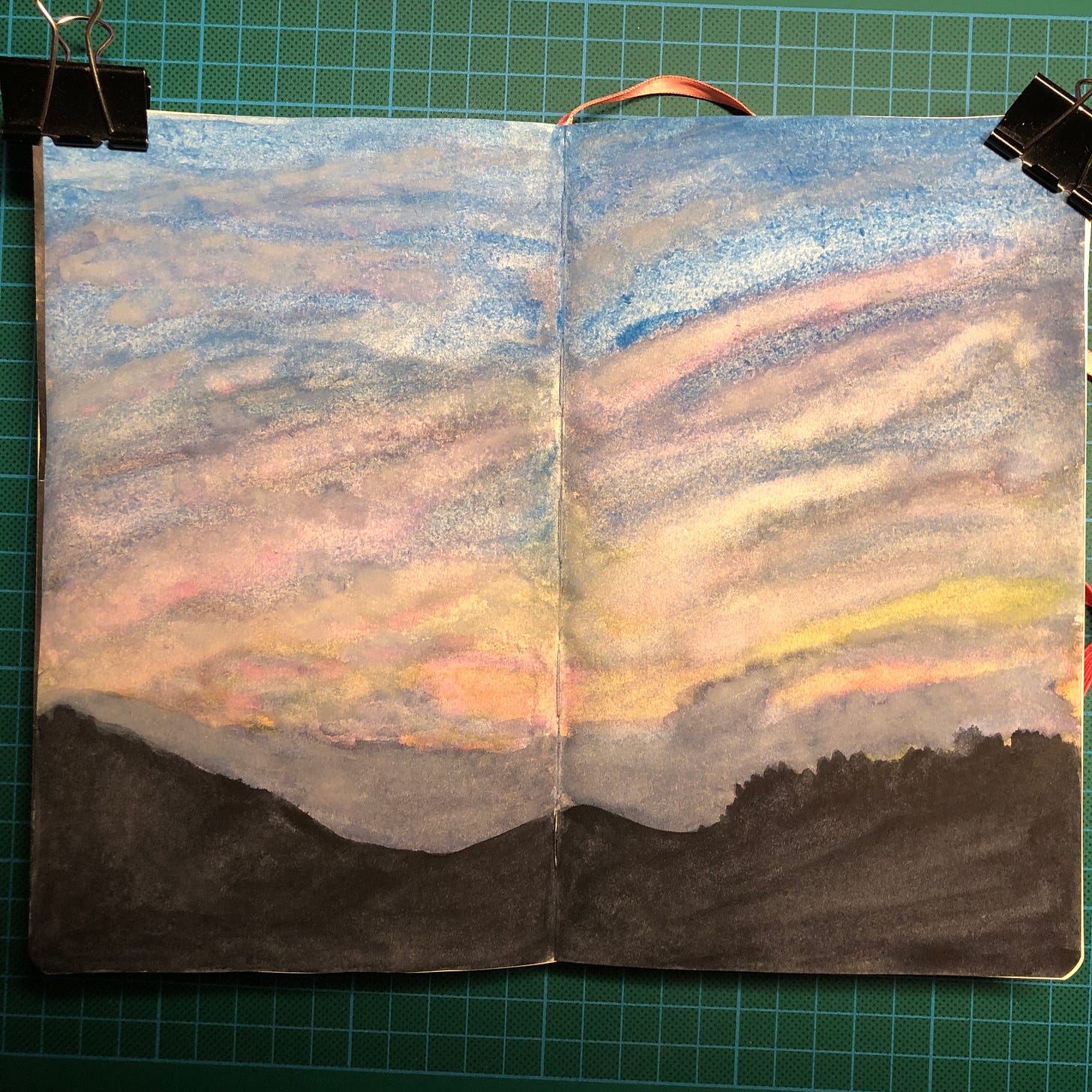 Photo de la double-page de mon sketchbook où j'ai peins ce ciel dramatique au-dessus de la silhouette noire d'une montagne. Photo de la double-page de mon sketchbook où j'ai peins ce ciel dramatique au-dessus de la silhouette noire d'une montagne.