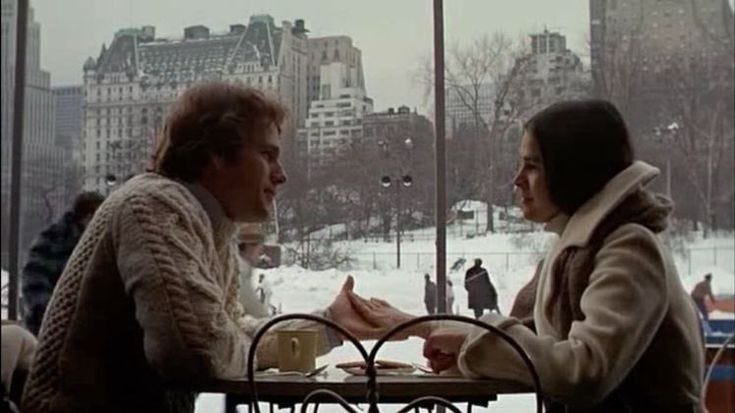 This may contain: two women sitting at a table in front of a window with snow on the ground