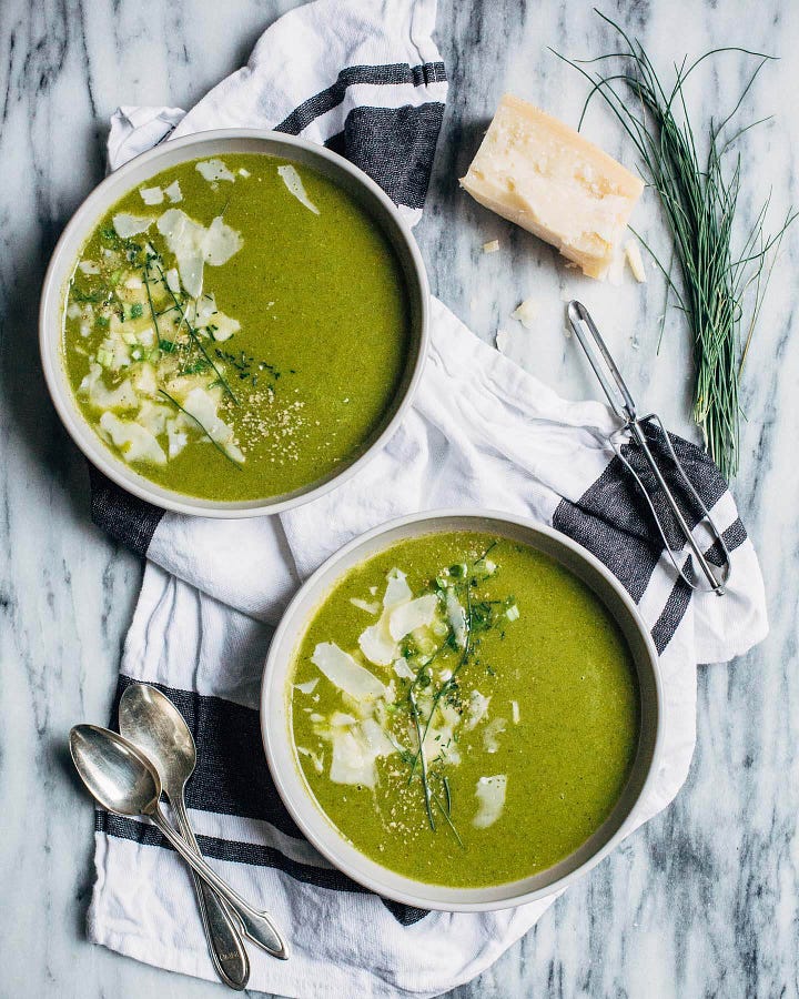 On the left, a plate of linguine with herbs and golden breadcrumbs, on the right, two bowls of green soup with cheese and chives alongside