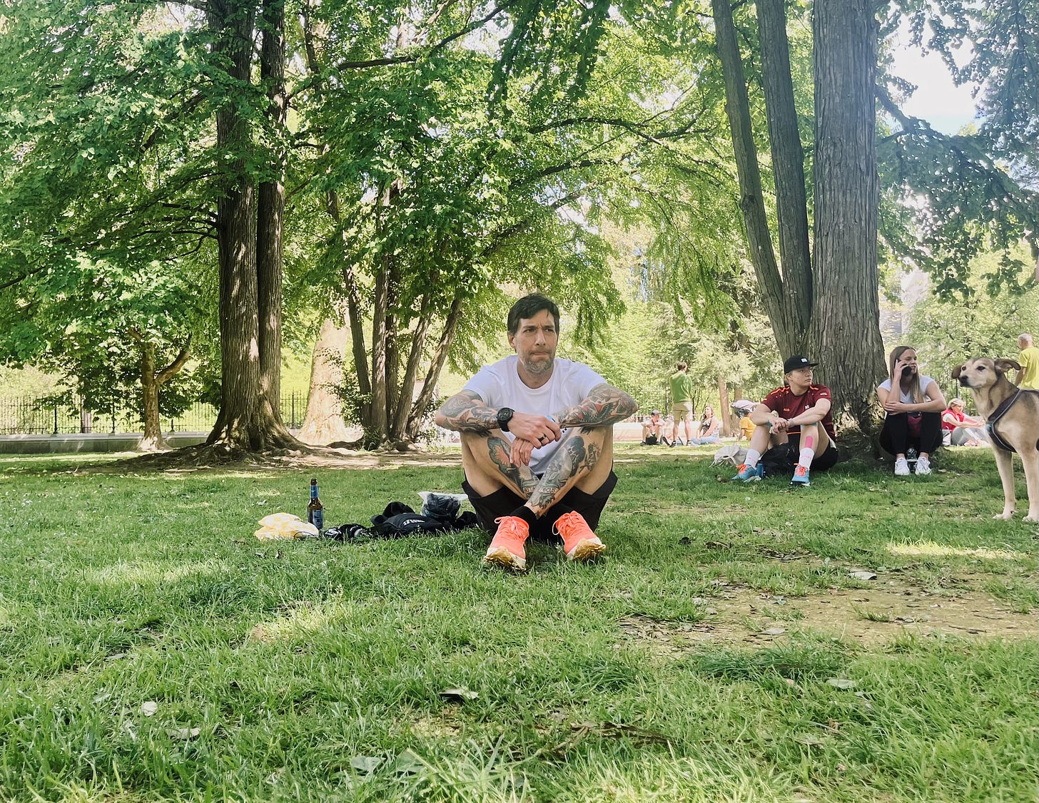 the author sitting on grass and a dog watching him 