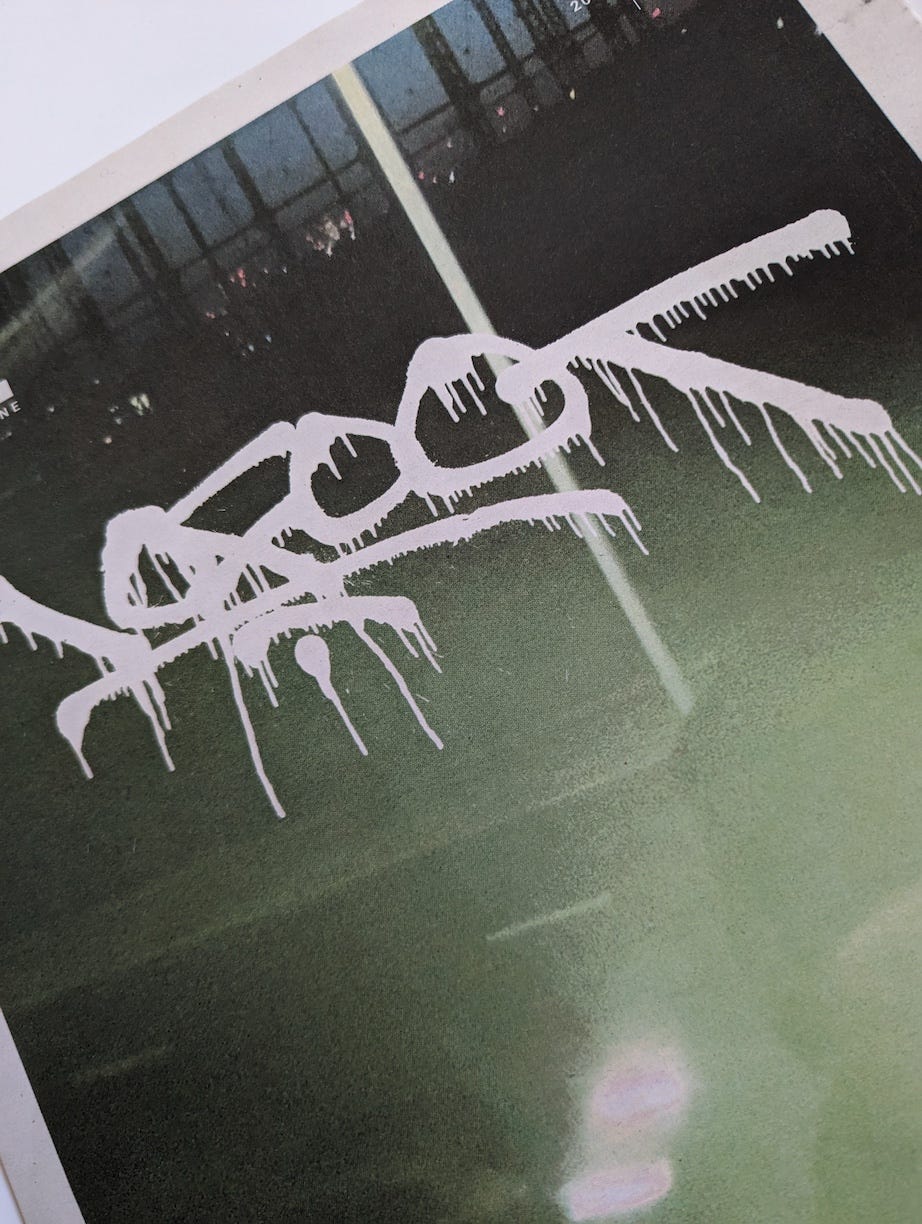 Detailed close-up of graffiti artist 10 Foot's signature handstyle on the cover of DOPE Magazine Issue 22. The white dripping tag contrasts against a blurred urban background, embodying raw street art aesthetics.