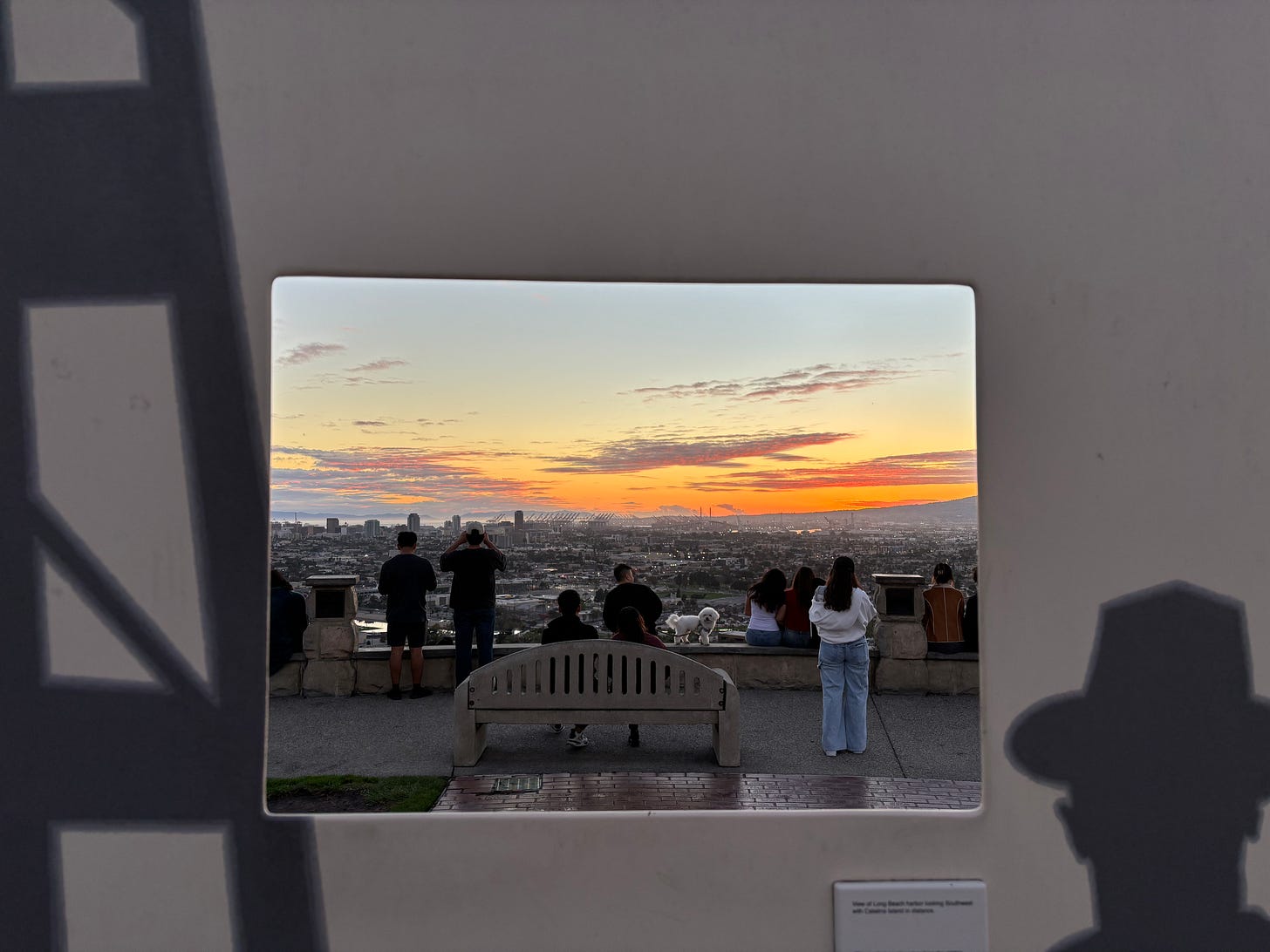 Image of people sitting on a bench overlooking the city at sunset