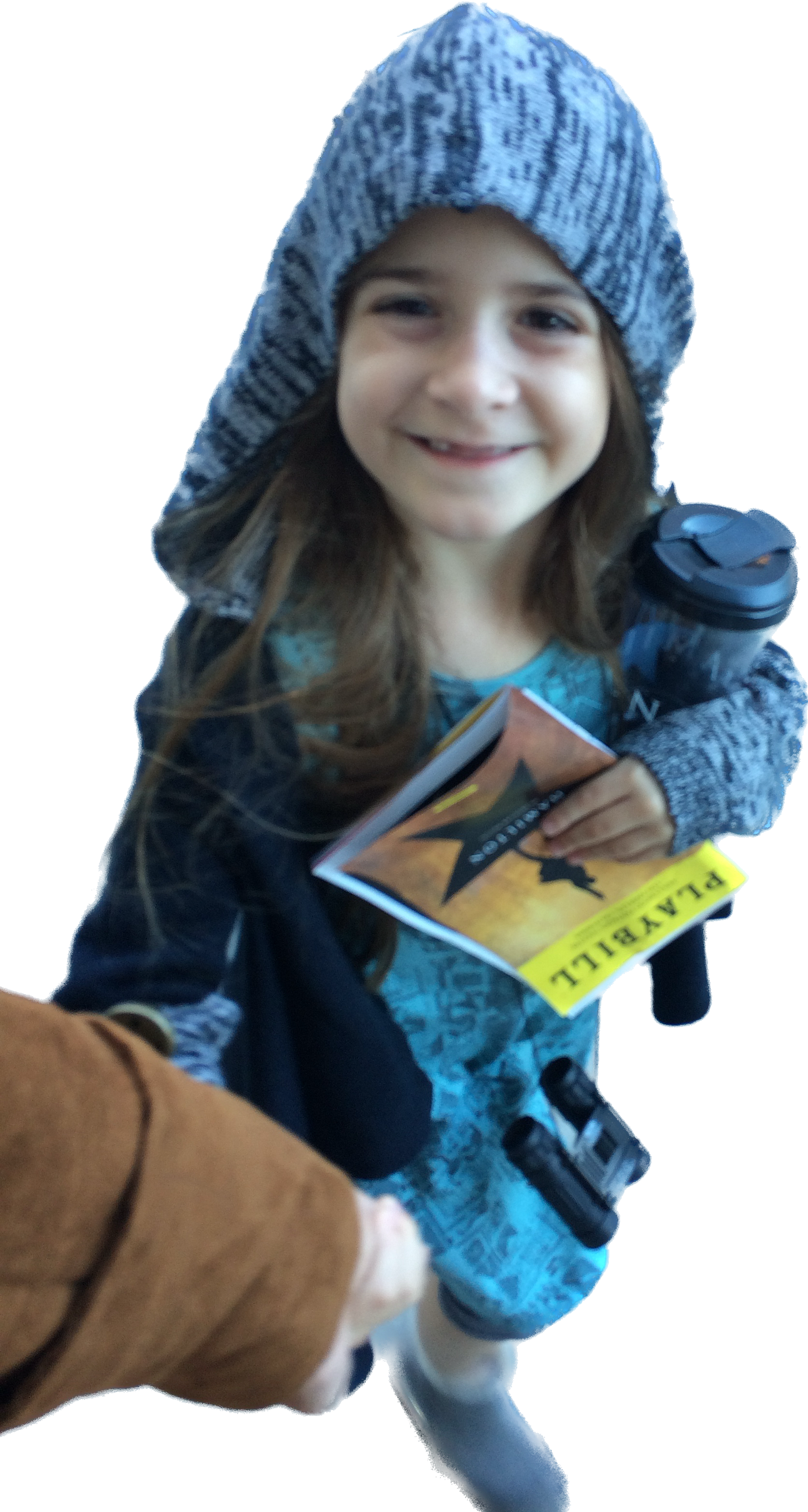 Little girl beams up at her dad, holiding his hand, with Hamilton playbill in the other