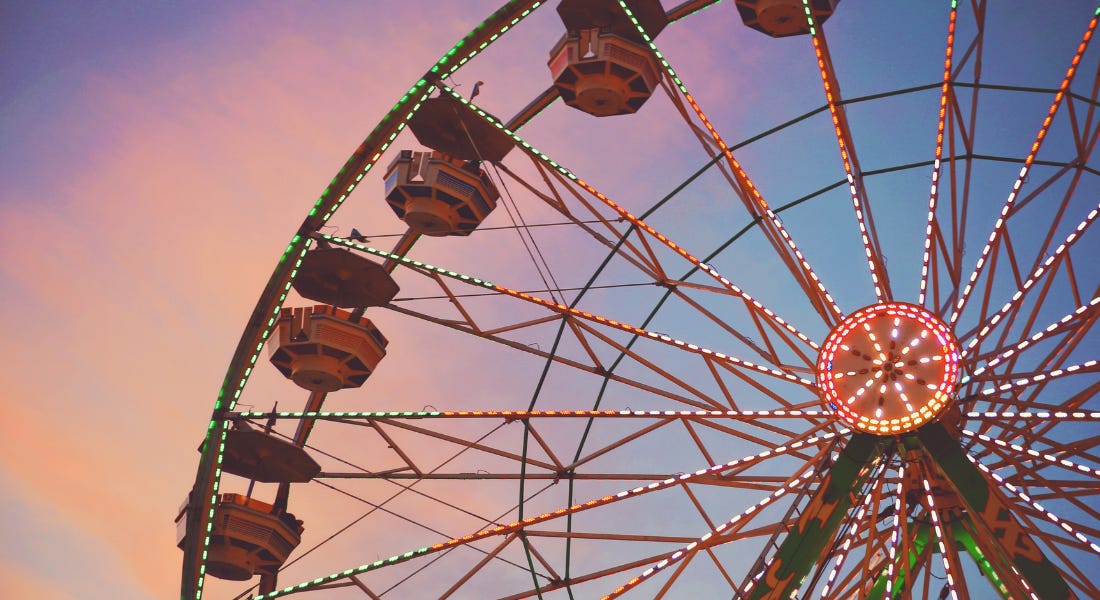 A red and green ferris wheel with a sunset sky behind it