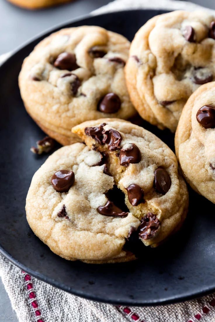 This may contain: chocolate chip cookies on a black plate This may contain: chocolate chip cookies on a black plate