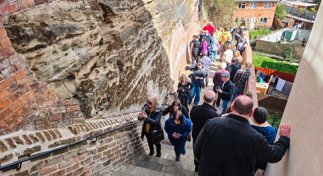A long set of stairs with a group of people walking up and down them, with a small terrace at the end