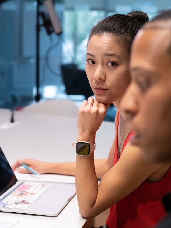 Free Woman in Red Tank Top Sitting Beside Her Co Worker Stock Photo